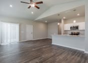 Thumbnail 11 of 22 - an empty living room with a kitchen and a ceiling fan
