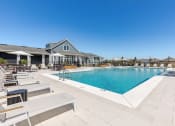 Thumbnail 13 of 22 - a swimming pool with lounge chairs and a building in the background