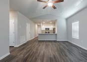 Thumbnail 12 of 22 - an empty living room with a ceiling fan and a kitchen