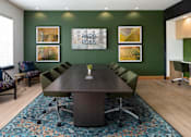 Thumbnail 21 of 28 - a conference room with green walls and a large wooden table with a vase of flowers on