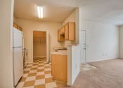Thumbnail 7 of 20 - Beaumont, TX Apartments – Breakwater Bay - Kitchen with tile flooring, stainless steel sink, plenty of cabinets for storage, oven/stove top, fridge, pantry. Living room with plush carpet.