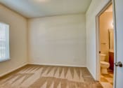 Thumbnail 11 of 20 - Pet-Friendly Apartments in Beaumont, TX – Breakwater Bay - Bedroom with plush carpet, window with coverings and door to private bathroom