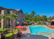 Thumbnail 2 of 24 - A swimming pool at Lake forest surrounded by beach umbrellas and beach chairs and trees