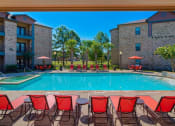 Thumbnail 11 of 24 - A swimming pool at Lake forest surrounded by beach umbrellas and beach chairs and trees