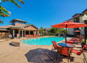 Thumbnail 12 of 24 - A swimming pool at Lake forest surrounded by beach umbrellas and beach chairs and trees