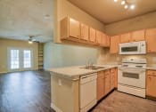 Thumbnail 1 of 24 - A living room and kitchen with wood flooring and wood cabinets with white dishwasher and white microwave and stove top with oven and steel sink