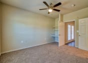 Thumbnail 5 of 24 - An empty living room with carpet and ceiling fan and shelves and doors