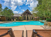 Thumbnail 14 of 25 - Mission oaks pool surrounded by trees and beach chairs and club house