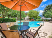 Thumbnail 16 of 25 - Mission oaks pool surrounded by trees and beach chairs and umbrella and club house