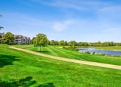 Thumbnail 18 of 18 - a golf course with a body of water and houses in the background