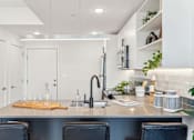 Thumbnail 33 of 78 - A modern kitchen with a stainless steel island and black chairs.