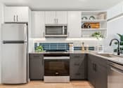 Thumbnail 34 of 78 - A modern kitchen with a refrigerator, microwave, oven, and sink.