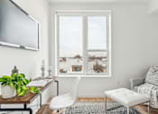 Thumbnail 19 of 78 - A living room with a white chair, a white ottoman, a white couch, a wooden coffee table, a potted plant, and a framed picture on the wall.