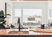 Thumbnail 35 of 78 - A modern kitchen with a wooden table and a large window overlooking the city.