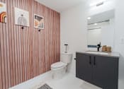 Thumbnail 49 of 78 - A bathroom with a toilet, sink, and striped wallpaper.
