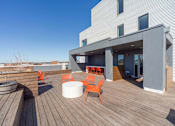 Thumbnail 36 of 78 - A modern deck with orange chairs and a white table.