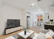 Thumbnail 23 of 78 - Contemporary living room with a neutral color scheme, featuring a sleek TV unit, comfortable white sofa, and an integrated dining area visible in the background.