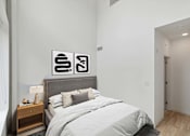 Thumbnail 60 of 78 - A bedroom with a bed, nightstand, and two framed pictures on the wall.