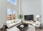 Thumbnail 16 of 78 - Spacious living room with high ceilings, featuring a sleek white sofa, contrasting black armchairs, and a view of the construction outside through large windows.