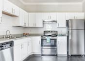 Thumbnail 1 of 39 - Affordable Houston Texas Apartments – Westchase Forest – Photo of upgraded kitchen with white cabinets and stainless steel appliances