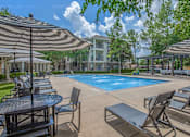 Thumbnail 2 of 39 - Affordable Houston Texas Apartments – Westchase Forest – Photo of our apartments offer a swimming pool with chairs and umbrellas