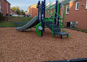 Thumbnail 10 of 13 - A playground with a green slide and a blue and green climbing frame.