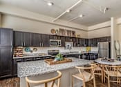Thumbnail 17 of 39 - A kitchen with a granite countertop and wooden chairs.