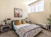 Thumbnail 18 of 39 - A bedroom with a bed, a nightstand, a plant, and a painting on the wall.