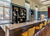 Thumbnail 21 of 39 - A long bar with yellow chairs and a counter with a clock on it.