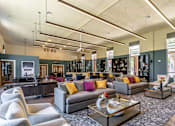 Thumbnail 23 of 39 - A modern living room with a grey sofa and a glass coffee table.