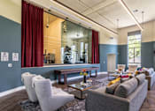 Thumbnail 25 of 39 - A living room with a grey couch, a coffee table, and a large mirror.