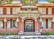 Thumbnail 32 of 39 - A red brick building with a black door and windows.