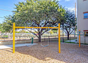 Thumbnail 34 of 39 - A playground with a swing set and a tree.