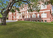Thumbnail 36 of 39 - A large red brick building with a tree in front.