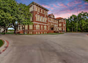 Thumbnail 35 of 39 - A large red brick building with a parking lot in front.