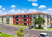 Thumbnail 37 of 39 - A large apartment complex with a parking lot in front.