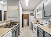 Thumbnail 1 of 18 - Nashville, TN Apartments - Parc at Metro Center - long kitchen with white appliances and wooden floors and Grey Cabinets
