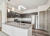 Thumbnail 1 of 33 - 1 & 2-Bedroom Apartments for Rent in Bentonville, AR – Parc at Bentonville – A kitchen with a granite countertop and stainless steel appliances.
