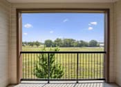 Thumbnail 21 of 33 - A balcony with a black railing and a view of a green field.