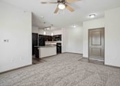 Thumbnail 15 of 33 - Apartments for Rent in Bentonville, AR 72713– Parc at Bentonville -   A spacious living room with a ceiling fan and a kitchen in the background.