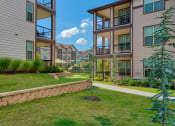 Thumbnail 26 of 33 - Pet-Friendly Rentals in Bentonville, AR – Parc at Bentonville – Exterior photo with trees and grass and building