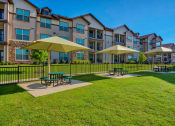 Thumbnail 24 of 33 - Park with tables and umbrellas and grass and building in back