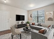 Thumbnail 1 of 25 - 1, 2 & 3-Bedroom Apartments for Rent in Maumelle, AR – Parc at Maumelle – A living room with a grey couch, a white door, a black TV and a plant on the coffee table.