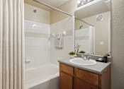 Thumbnail 9 of 25 - A bathroom with a white tub, sink, and a mirror.