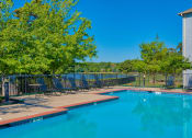 Thumbnail 14 of 25 - Pet-Friendly Rentals in Maumelle, AR – Parc at Maumelle – a swimming pool surrounded by trees and beach chairs