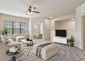 Thumbnail 6 of 25 - A living room with a ceiling fan and a flat screen TV.