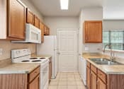 Thumbnail 4 of 25 - A kitchen with white appliances and wooden cabinets.
