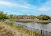 Thumbnail 20 of 25 - Parc at Rogers exterior building with a pond in front surrounded by a gate