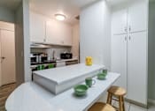 Thumbnail 2 of 15 - Hayward, CA Apartments Near Hayward BART Station - Paseo Gardens - Kitchen with White Cabinetry, Stainless Steel Appliances, Granite Countertops, Large Pantry Doors, Large Island with Seating and Breakfast Bar Section, and Tile Flooring