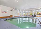 Thumbnail 24 of 34 - A large indoor swimming pool with a diving board.